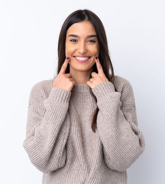 Happy young woman pointing at her smile