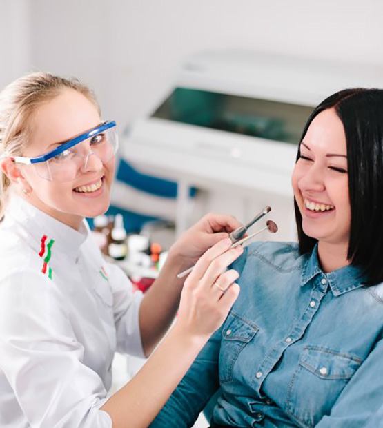 Dentist smiling while working on a female patient