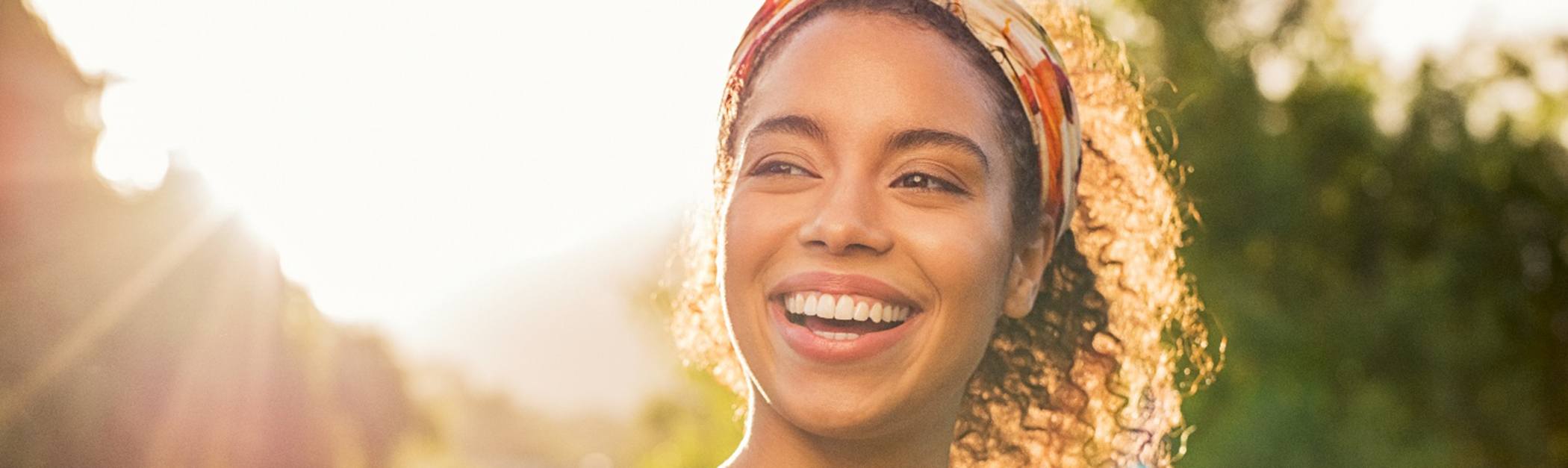 Young female outside and smiling after receiving her dental crowns in Encino
