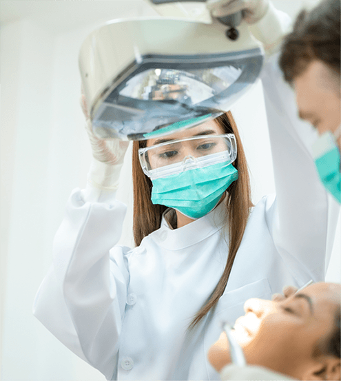 Dentist aiming the light over a patient’s mouth in preparation for crown placement