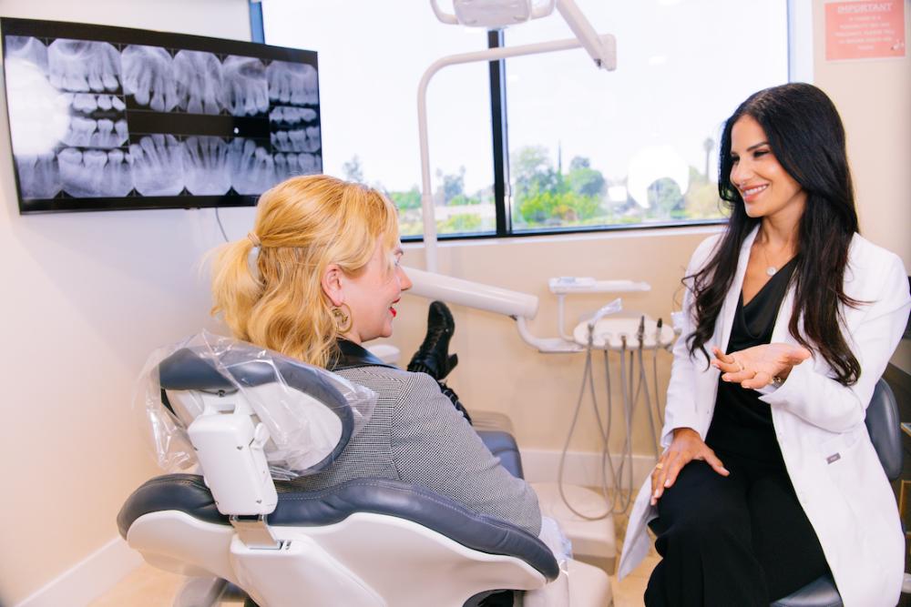 Woman smiling with dr mahooti in dental chair, encino ca