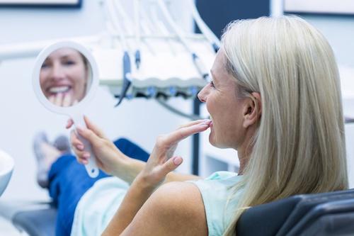 Older woman looking at teeth with veneers, encino ca