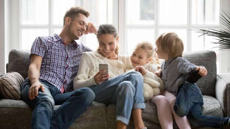 Mom and dad and kids smiling together on a couch, encino ca