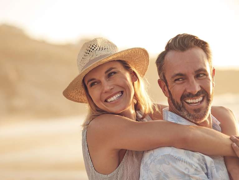 Man and woman on beach embracing and smiling, encino ca